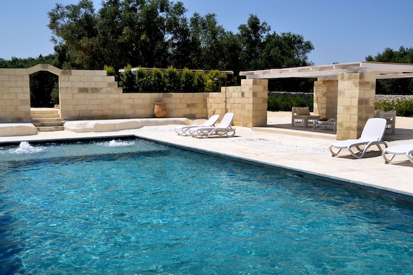 Una piscina al aire libre, sombrillas, tumbonas