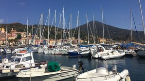 A marina with multiple boats docked, a clear sky, and buildings in the background. - Rio Marina studio apartment in a characteristic residence 10 meters from the sea (Rio Marina)