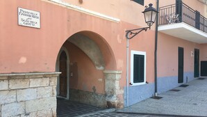A building with a sign indicating a pizza place, an arched doorway, and a small balcony with a railing. - Rio Marina studio apartment in a characteristic residence 10 meters from the sea (Rio Marina)