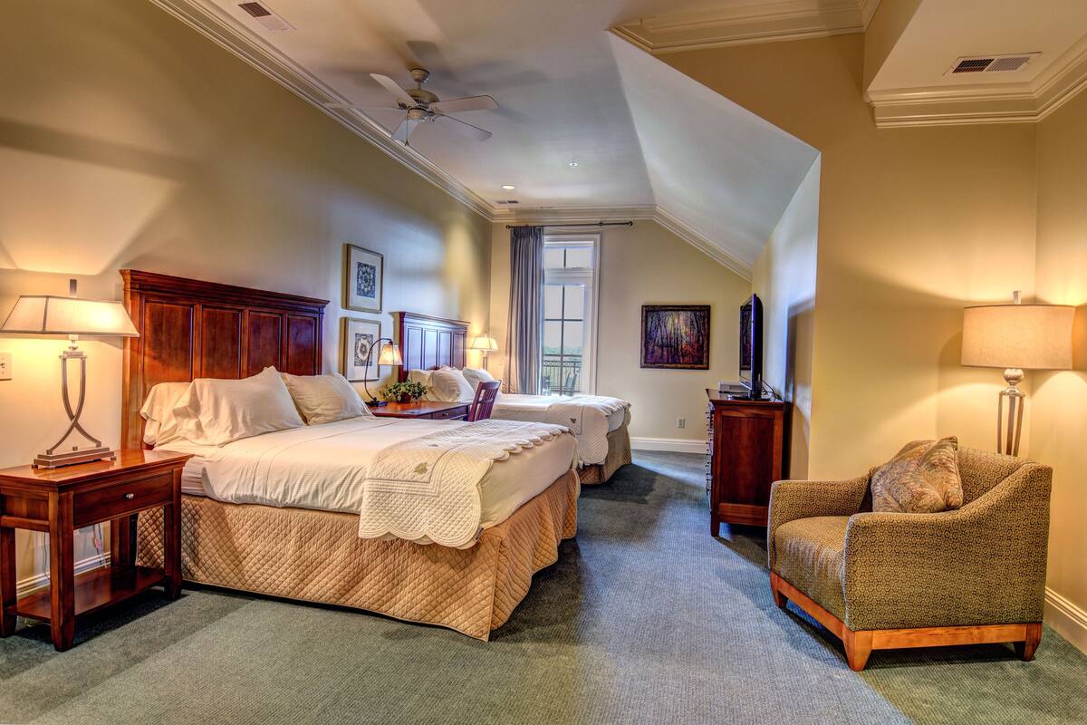 A bedroom with two beds, a chair, and a ceiling fan.