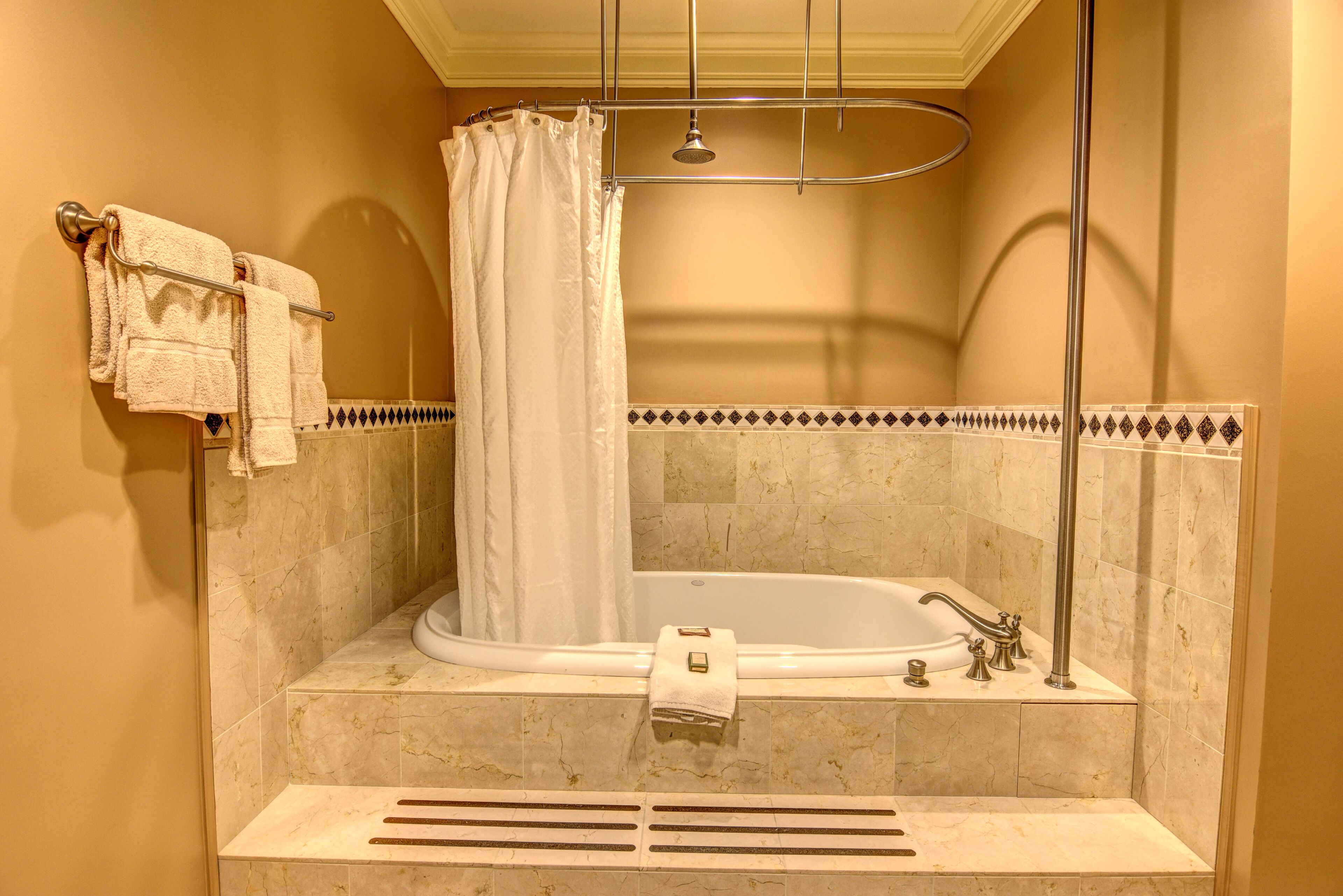 A bathroom with a bathtub, a shower curtain, and a towel rack with towels.