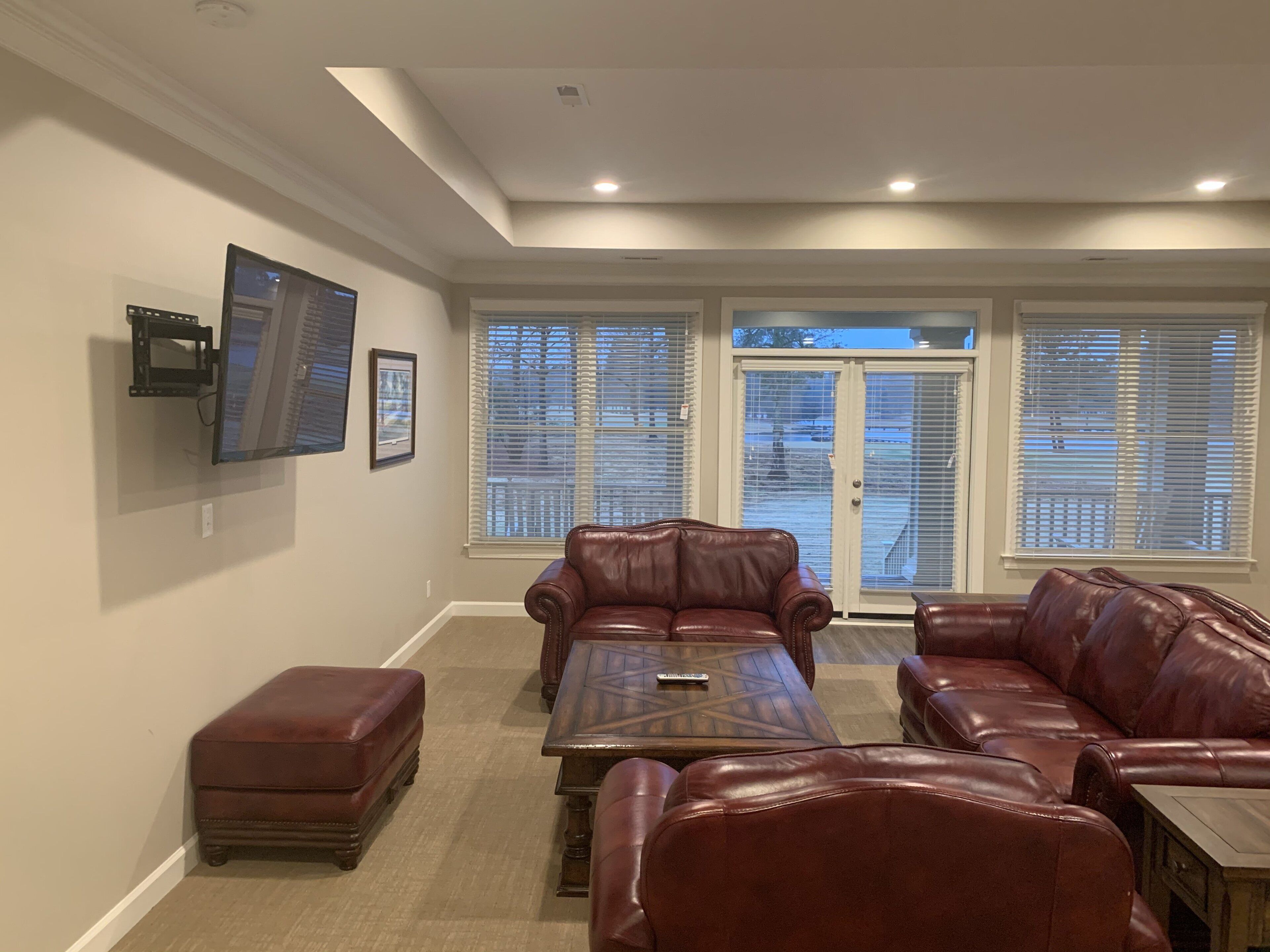 A living room with two leather sofas, a coffee table, and a TV mounted on the wall.