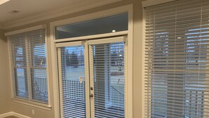 A room with a sliding glass door and three windows with blinds. - The Village at RiverLanding (Wallace)