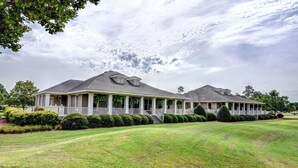 A large, two-story house with a covered porch and a well-maintained lawn. - The Village at RiverLanding (Wallace)