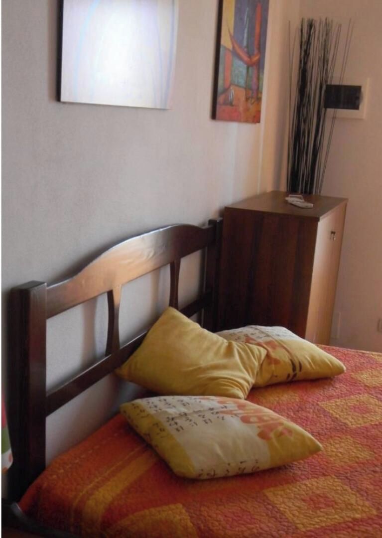 A bed with a wooden headboard, two pillows, and a patterned bedspread.