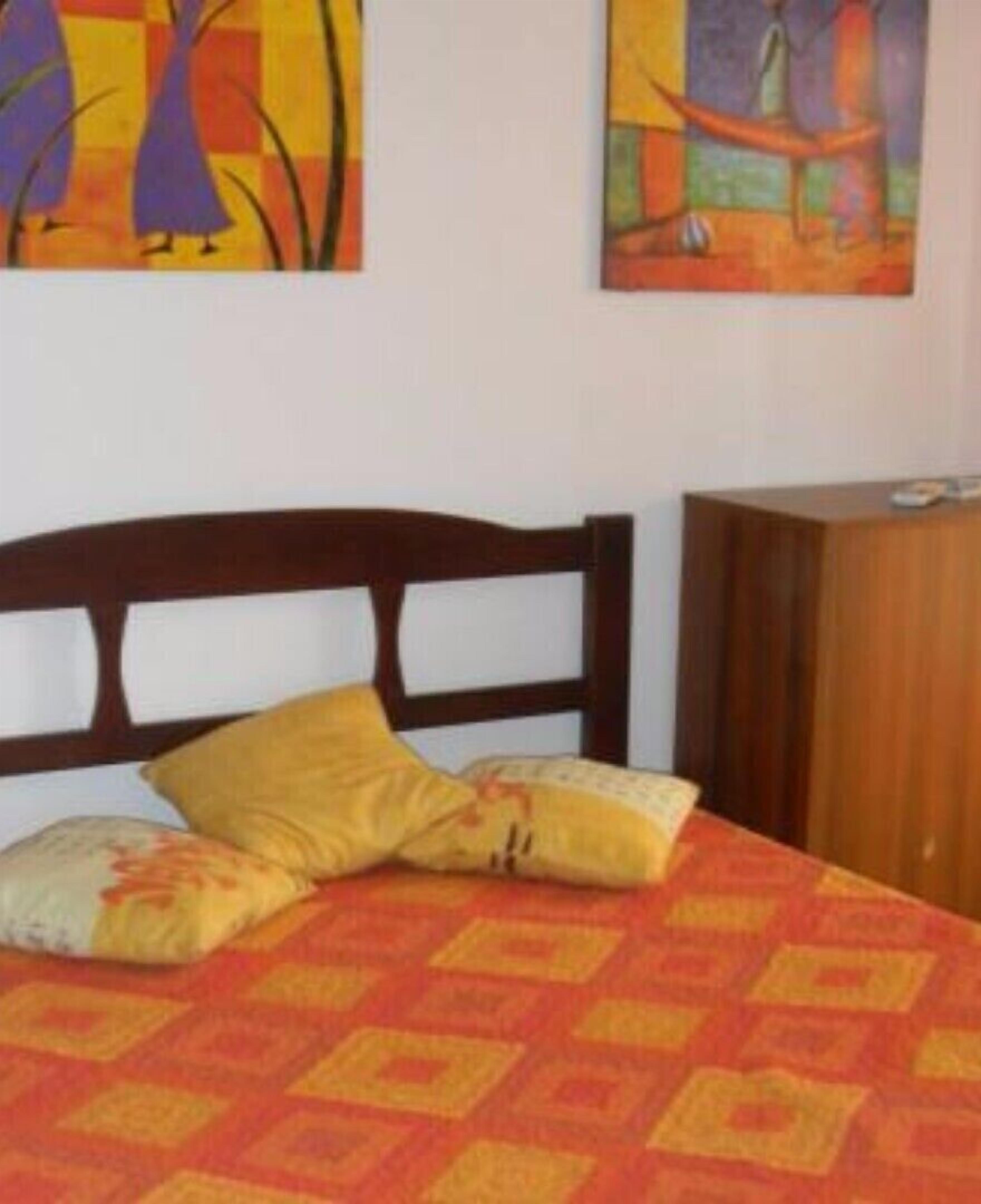 A bed with a patterned bedspread, two pillows, and a wooden headboard.