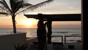 Relax in a serene oceanfront setting with a shaded pergola, lounge chairs, and scenic views.
