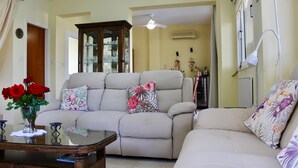 A living room with a beige sofa, a glass coffee table, and a vase with red roses. - The Carolyn villa in Ayia Napa has everything you need for an enjoyable holiday (AYIA NAPA)