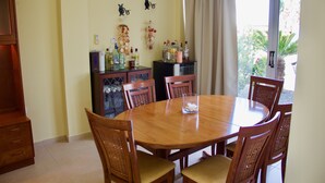 A dining area with a round wooden table and six chairs, a cabinet with various bottles, and wall decorations. - The Carolyn villa in Ayia Napa has everything you need for an enjoyable holiday (AYIA NAPA)