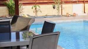 A poolside area with a table and chairs, a wooden fence, and potted plants. - The Carolyn villa in Ayia Napa has everything you need for an enjoyable holiday (AYIA NAPA)