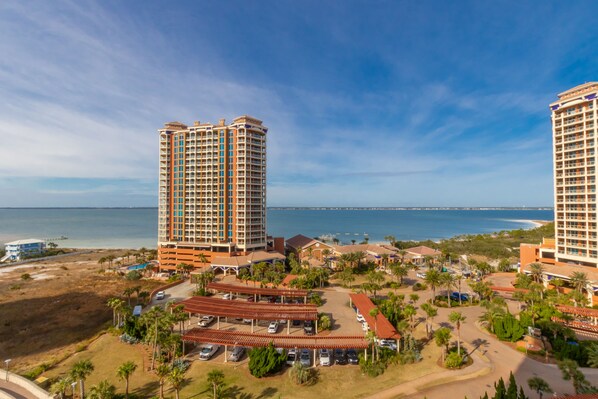 A high-rise hotel with multiple floors, a parking area, and a beach view. - 1 Portofino 1005 (Pensacola Beach)