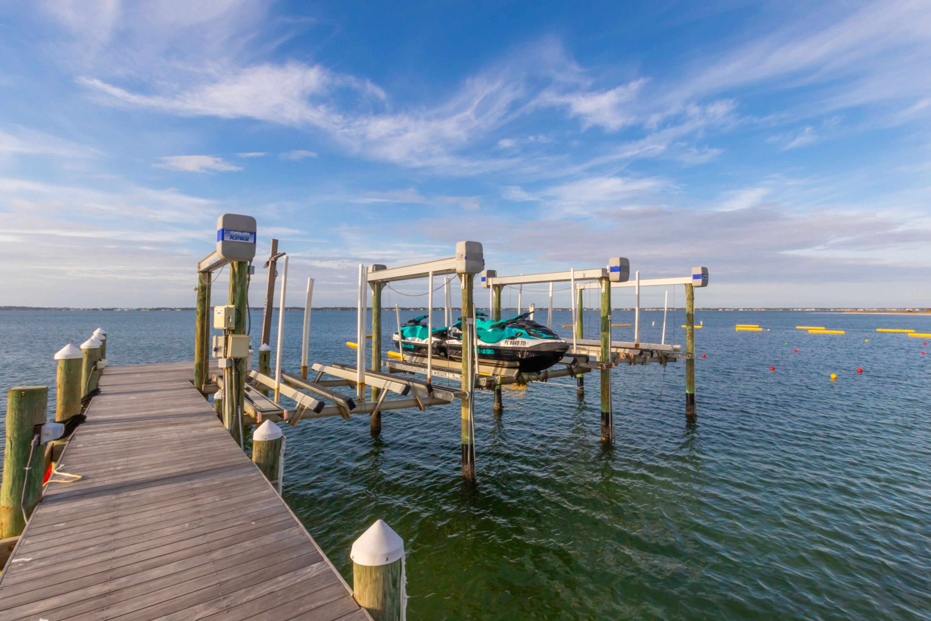 A wooden pier leading to a dock with a boat moored at the end.