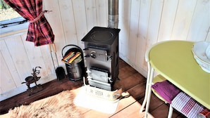 Un poêle à bois dans une pièce où se trouvent une table verte, une serviette violette et une figurine de cerf.