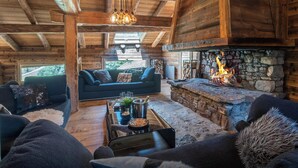 A cozy log cabin interior with a stone fireplace, a sofa, and a coffee table. - Chalet Victorina - stunning ski home for 12, close to slopes - OVO Network (La Giettaz)