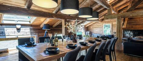 A wooden interior with a long dining table set for six, surrounded by chairs.