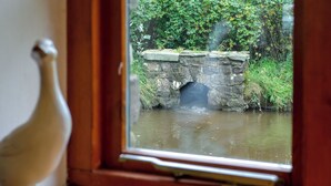 A view through a window of a stone bridge over a calm river, with greenery on the banks. - 2 bedroom accommodation in Llangennith, near Swansea (Llangennith, near Swansea)