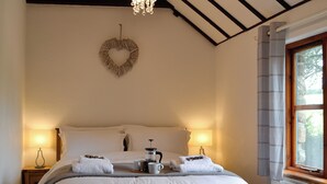 A neatly made bed with white linens, a heart-shaped decoration on the wall, and a window with curtains. - 2 bedroom accommodation in Llangennith, near Swansea (Llangennith, near Swansea)