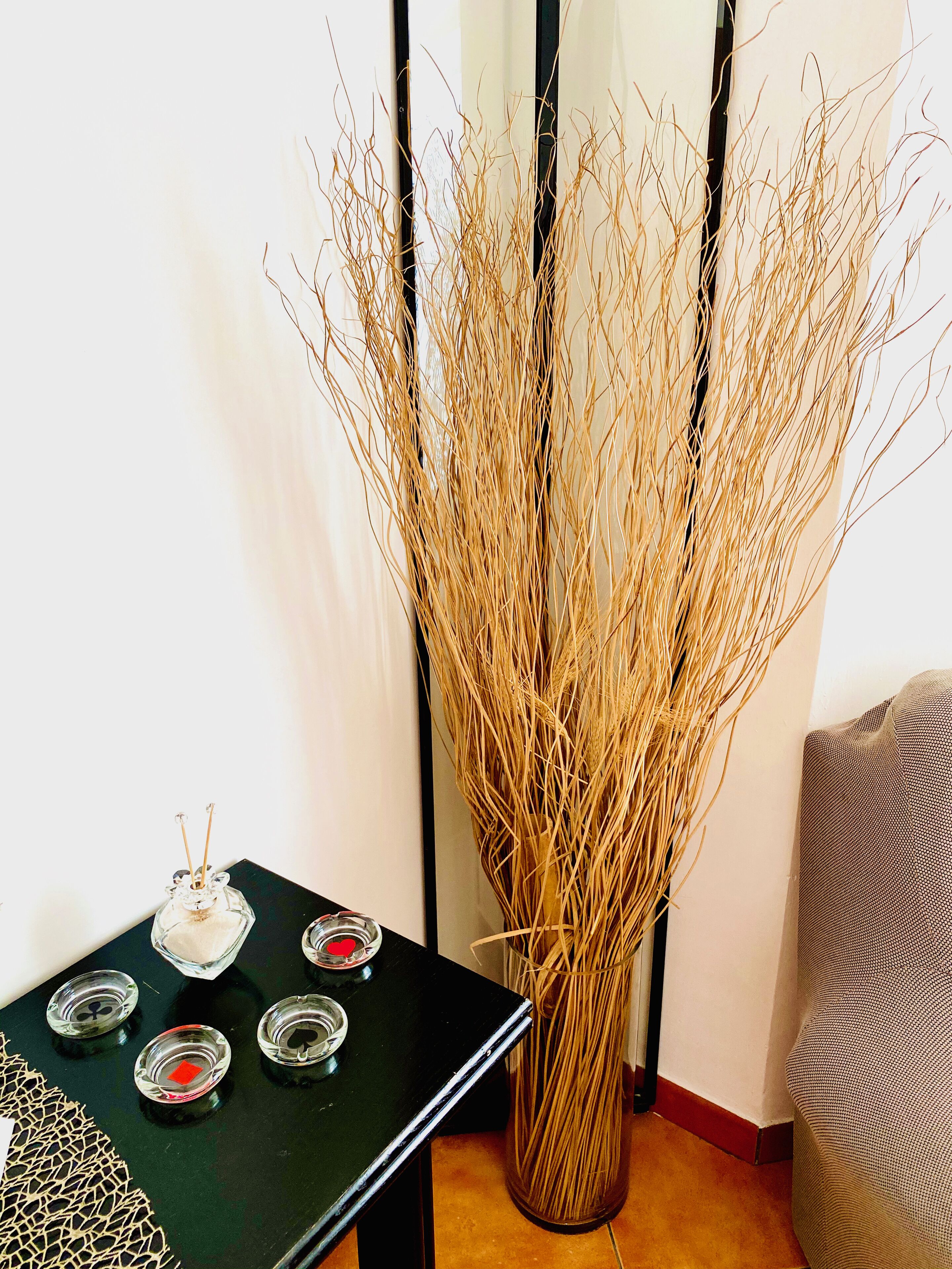 A table with a vase of dried branches and a decorative item with a red heart.