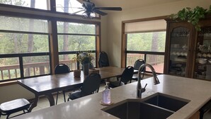 A kitchen with a large window, a dining area, and a built-in cabinet with glassware.