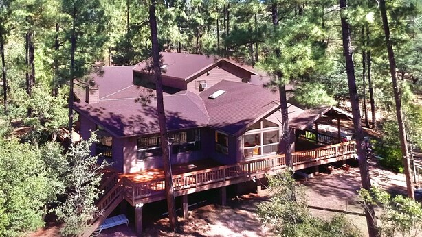 A cabin with a deck, surrounded by trees.