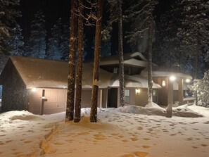 Set amidst snow-covered trees, this building offers a serene winter retreat with a sloped roof and multiple windows.