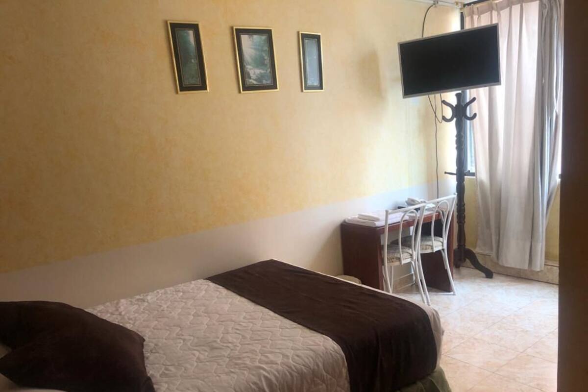 Una habitación de hotel con una cama, un escritorio y una televisión.