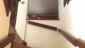 A wooden staircase with a handrail, a ceiling fan, and a wall-mounted light fixture. - Hostal La Cocina Tipica (Guayllabamba)
