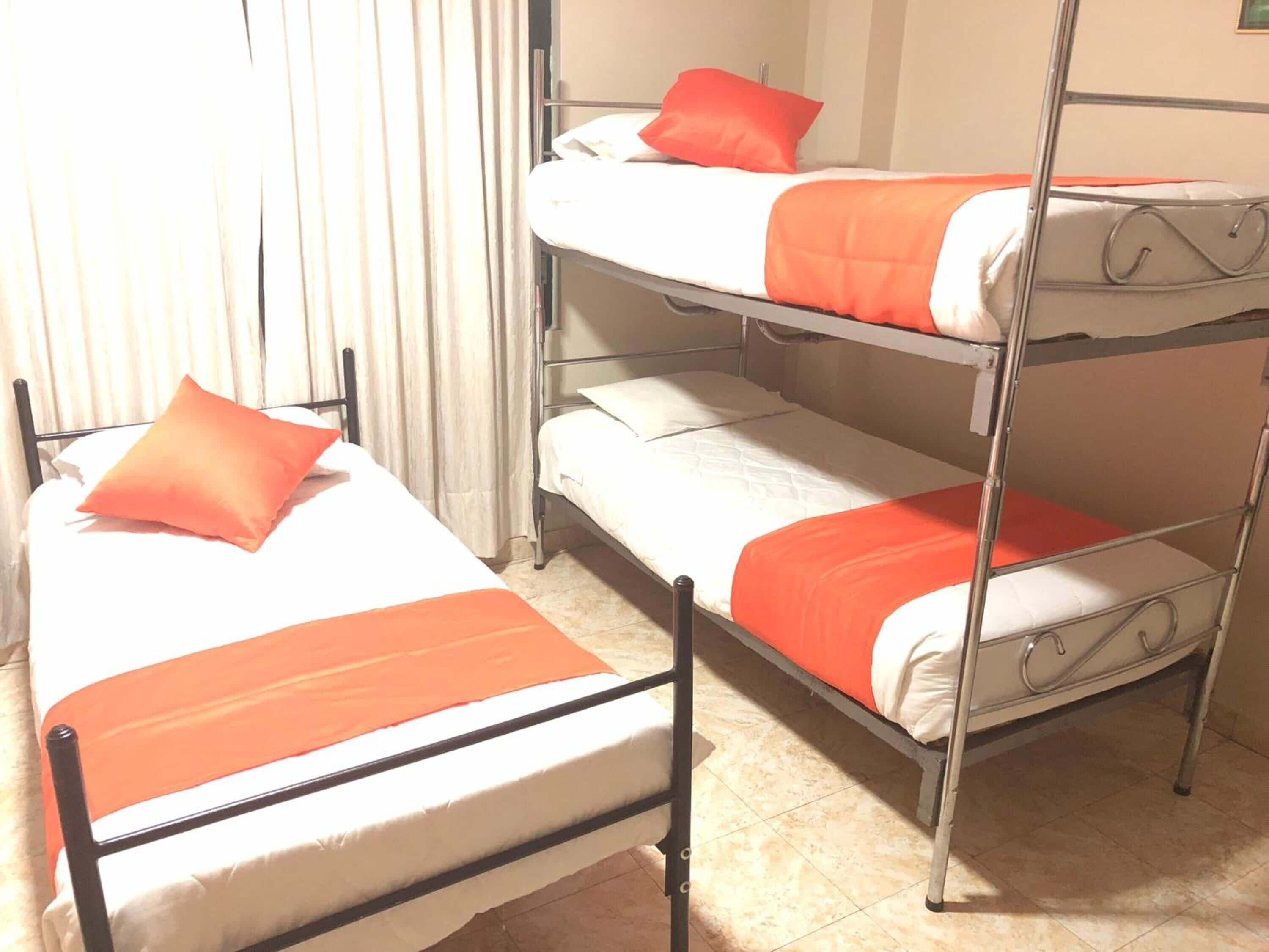 Habitación con literas, dos camas, cada una con ropa de cama naranja.