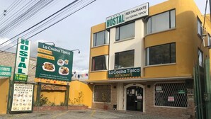A hostel with a yellow facade, a signboard advertising typical cuisine, and a Visa payment option. - Hostal La Cocina Tipica (Guayllabamba)