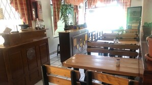 A restaurant interior with wooden tables and benches, a counter with a menu board, and potted plants. - Hostal La Cocina Tipica (Guayllabamba)
