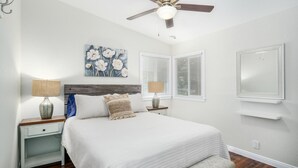A bedroom with a bed, two bedside tables with lamps, a ceiling fan, a painting, and a window with blinds. - Fully Refurbished Home for up to 9 Visitors (Fresno)