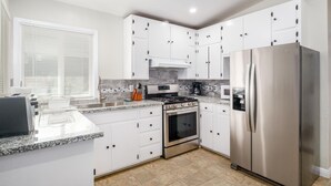 A modern kitchen with white cabinets, stainless steel appliances, and a tiled backsplash. - Fully Refurbished Home for up to 9 Visitors (Fresno)