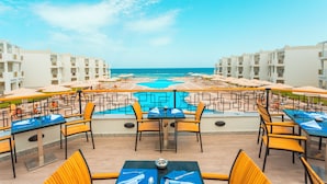 A poolside area with tables and chairs, a pool, and a view of the ocean. - Fantazia Marsa Alam Resort (Marsa Alam)