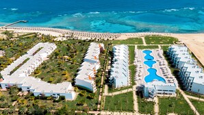 An aerial view of a resort with multiple buildings, a beach, and a large pool area. - Fantazia Marsa Alam Resort (Marsa Alam)