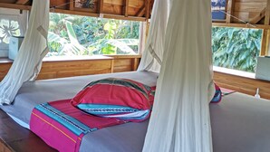 A wooden cabin with a bed under a canopy.