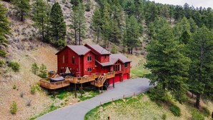 Une maison rouge à deux étages, dotée d’une terrasse et d’une allée.