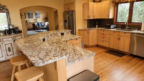 A kitchen with a granite countertop, wooden cabinets, and a stainless steel refrigerator. - Hummingbird Haven - Private Creek (Conifer)