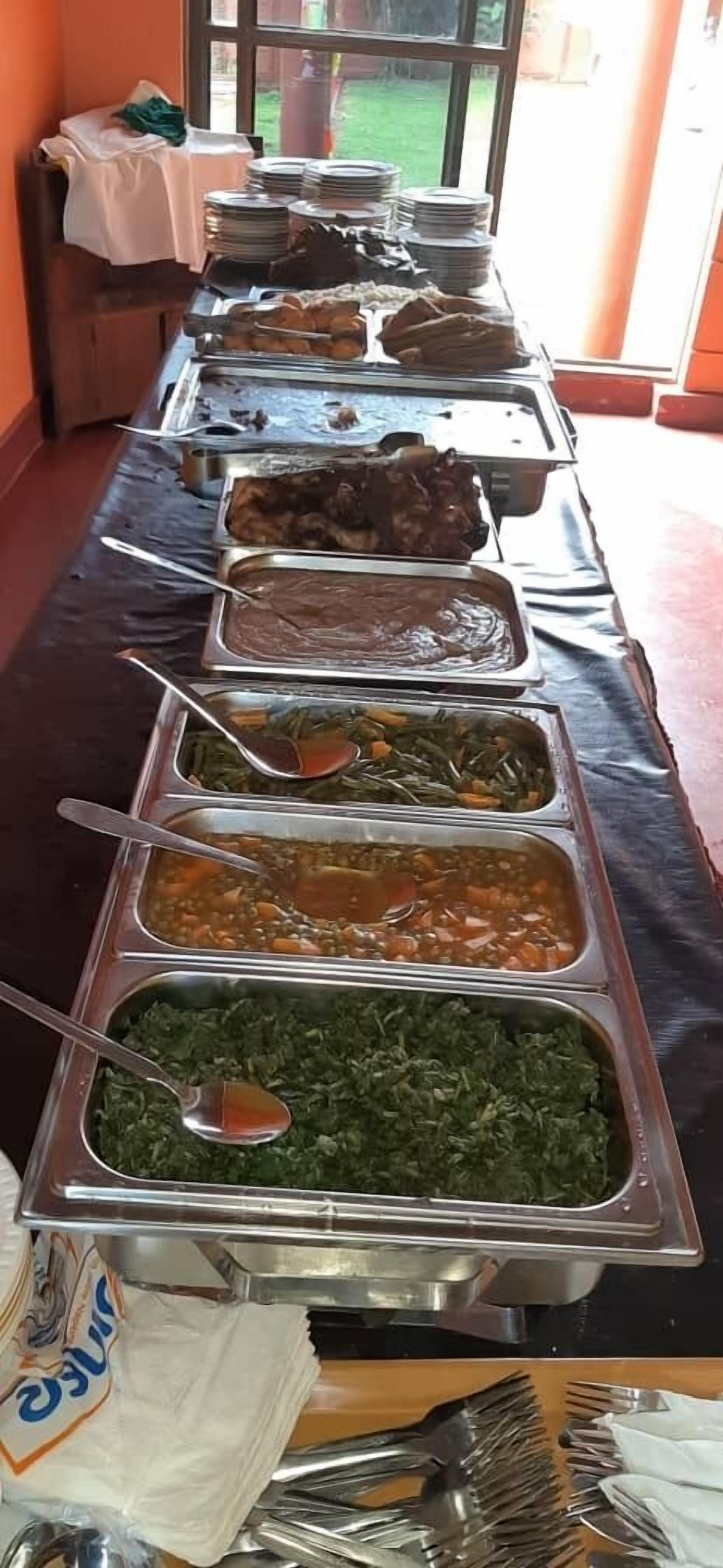 A buffet table with various food items and utensils.