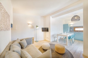 A modern living room with a sofa, ottoman, and a dining area with chairs and a table.