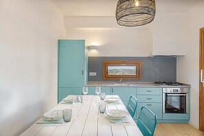 A compact kitchen with teal cabinetry, a built-in oven, and a window above the sink.