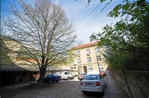 A narrow street with parked cars and a building with multiple windows and balconies. - Luxury Spa Apartment (Zagreb)