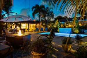 A poolside area with a fire feature, lounge chairs, and potted plants.