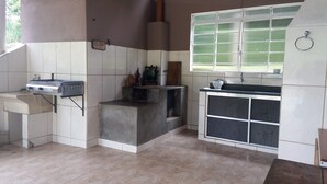 A compact kitchen with a gas stove, a sink, and a window with blinds. - Chacara Recanto Paraíso is in a privileged location. (Serra Negra)