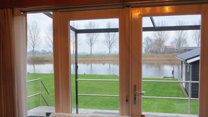 Een kamer met uitzicht op een meer, een grasveld en een gebouw aan de overkant van het water.