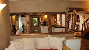 Une pièce chaleureuse avec un grand miroir qui reflète un coin cuisine, un lit avec de nombreux oreillers et un petit radiateur blanc.
