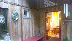 Un bâtiment en bois avec un banc et une porte donnant sur l’intérieur.