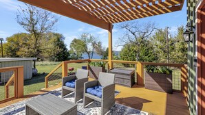 Une terrasse couverte, dotée de meubles en osier et offrant une vue sur le paysage environnant.