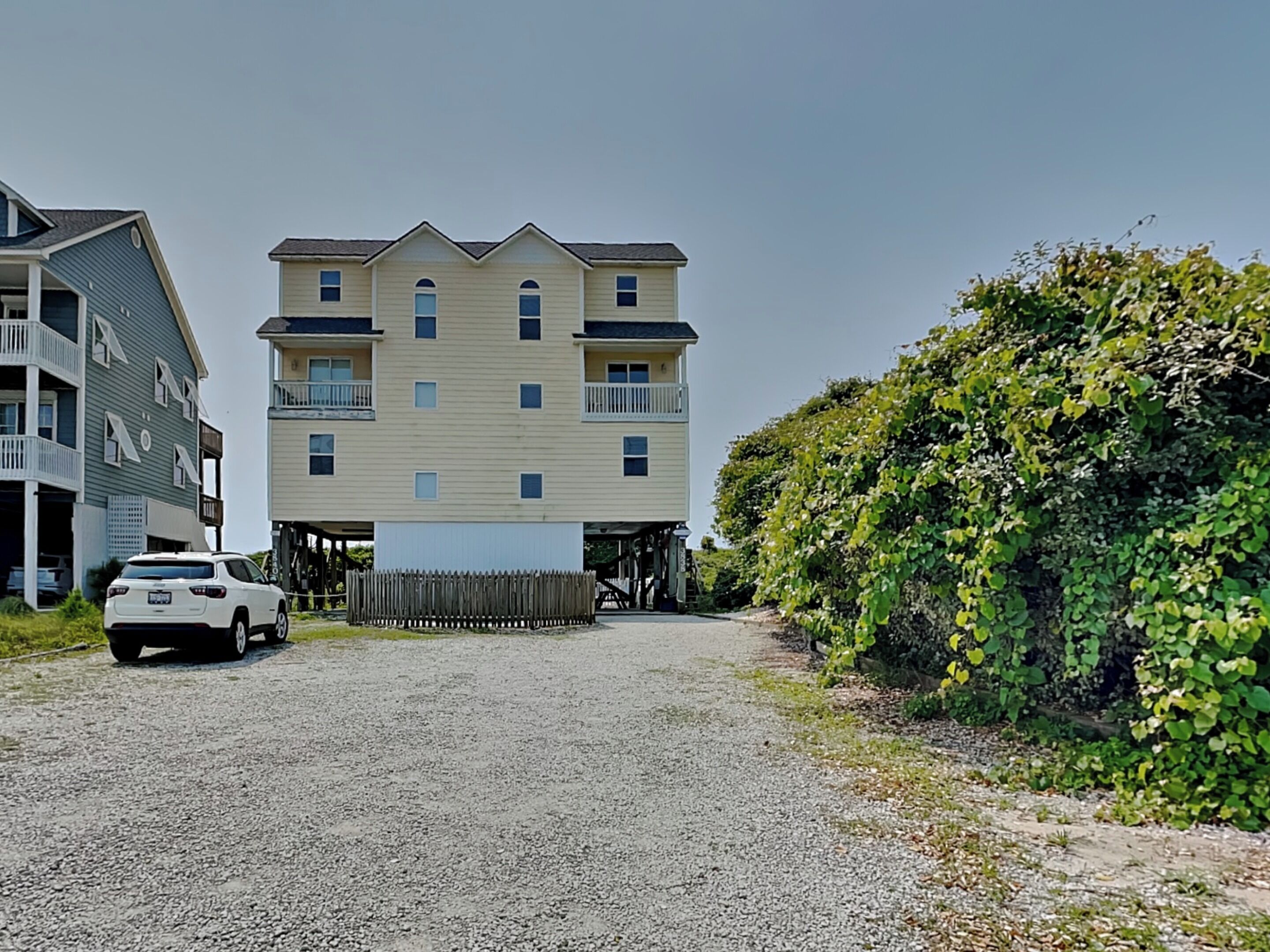 A multi-story building with a gravel driveway and a white car parked in front.
