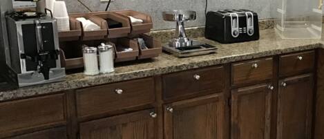 Una cocina con cafetera, tostadora y armarios.
