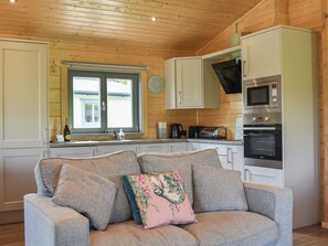 A cozy kitchen with a sofa, a microwave, and a window with a view.